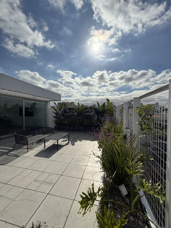 Vista amplia de la terraza con canteros perimetrales y la ciudad de fondo