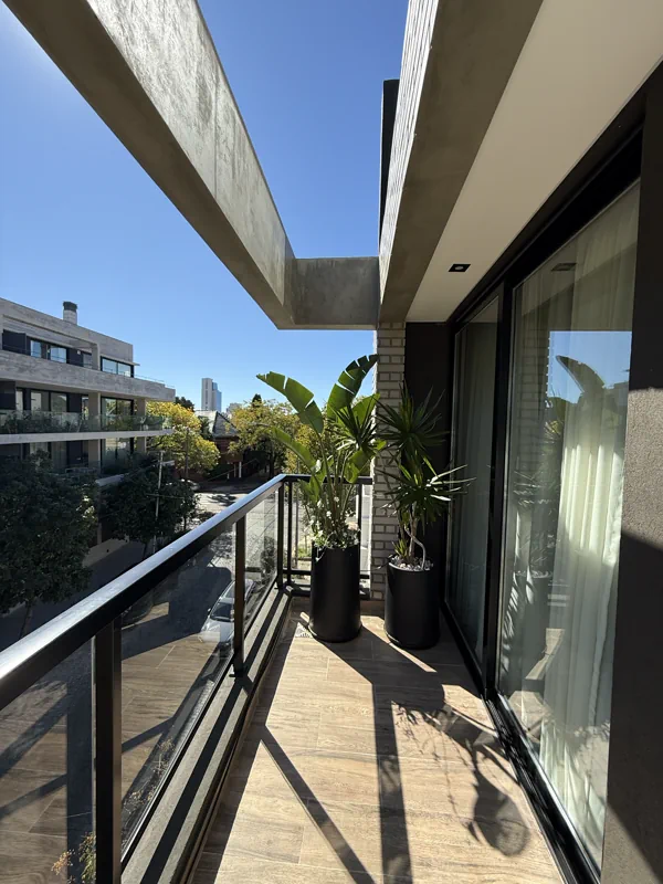 Vista longitudinal del balcón con macetas tropicales